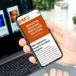 Mobile screenshot of BIM Tek website: orange banner reads 'Innovative surveying, design & BIM solutions' with the BIM Tek logo on screen, held in a hand